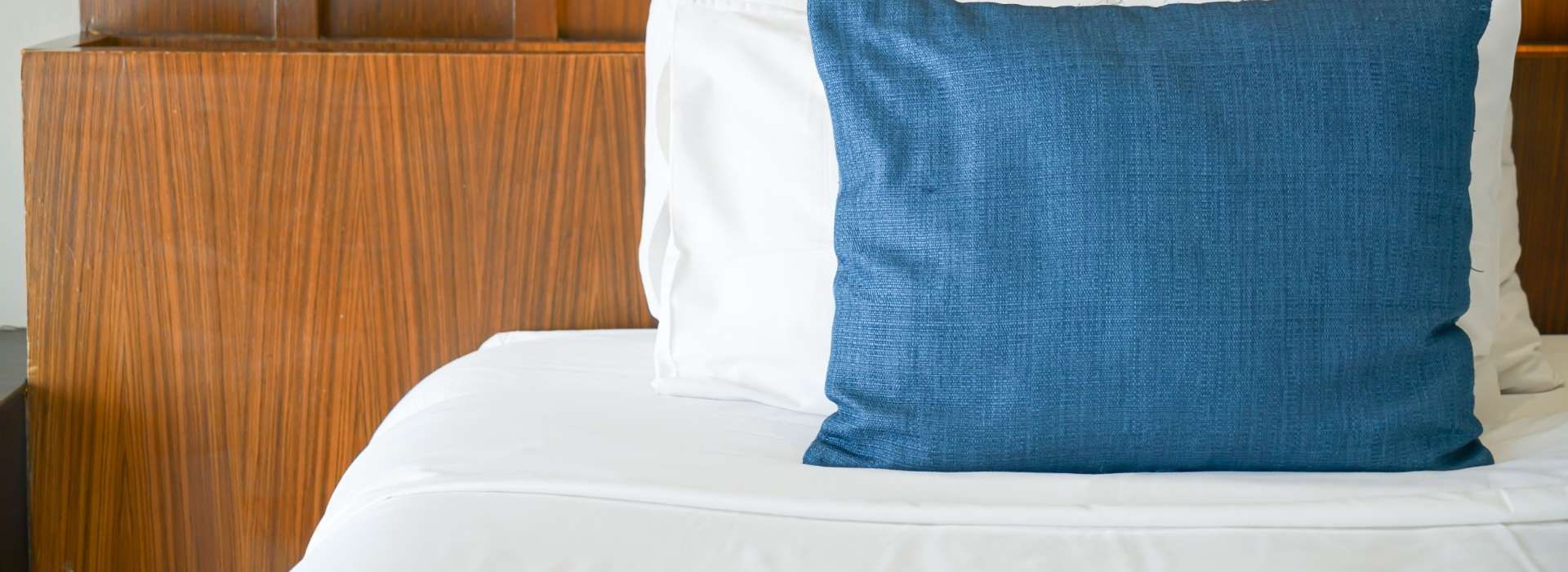 Cama con almohada blanca y otra azul